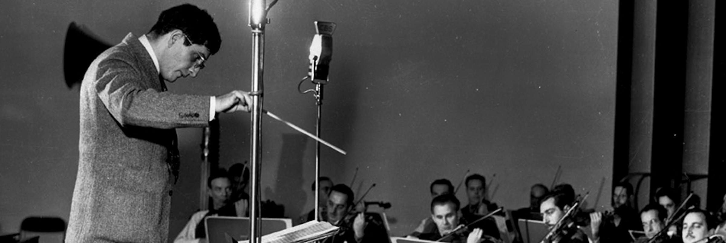 Bernard Herrmann conducting his orchestra, in black and white