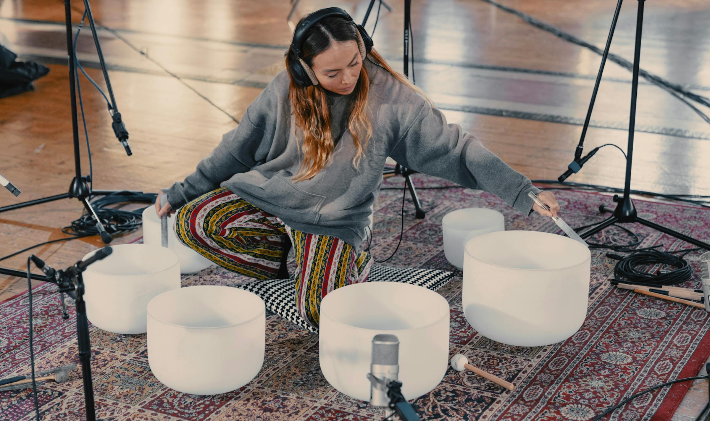 Aska performing surrounded by crystal bowls and mics in a circle